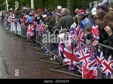 Early morning spectators holding their Union Jack flags waiting to see Britain's Queen Elizabeth II outside Buckingham Palace. The Queen and the Duke of Edinburgh will leave Buckingham Palace in a State Gold Coach for a thanksgiving service at St Paul's Cathedral. * ...  before returning to watch a parade in The Mall on the final day of the Golden Jubilee Bank Holiday weekend. Stock Photo