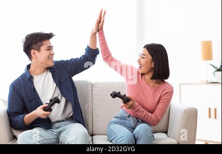 Chinese Girlfriend And Boyfriend Playing Videogame Using Games Console  Sitting On Floor At Home. Computer Gaming And Videogames For Couple, Family  Weekend Leisure Concept Stock Photo, Picture and Royalty Free Image. Image