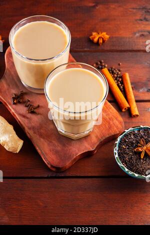 Milk tea and spices. Masala chai tea on wooden boards. Two glasses of masala tea and ingredients for making it. Copy space. Top view Stock Photo