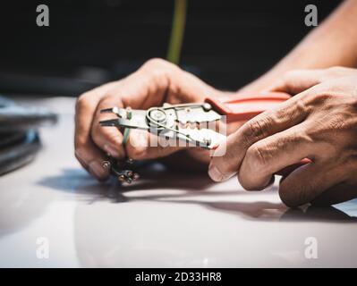 Closeup at the hand of an electrician is using electrical stripping pliers in industrial applications. Stock Photo