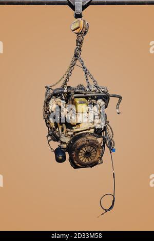 The old engine of the car hung on the hoist isolated on pastel color background, with clipping path. Stock Photo