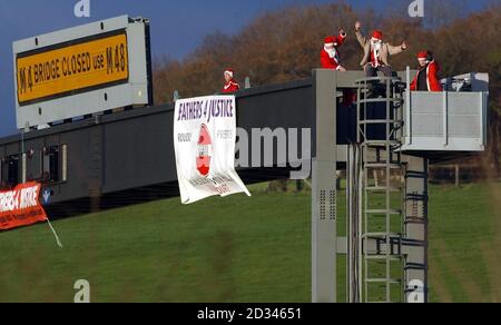 Four members of campaign group Fathers 4 Justice supporters dressed as Father Chistmas during a demonstration on a road gantry over the M4 motorway close to the Second Severn Crossing. Stock Photo