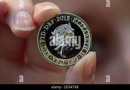 An event assistant from The Royal Mint holds a new two pound coin in during an unveiling ceremony for the latest coinage portrait of Queen Elizabeth II at the National Portrait Gallery, London. Stock Photo