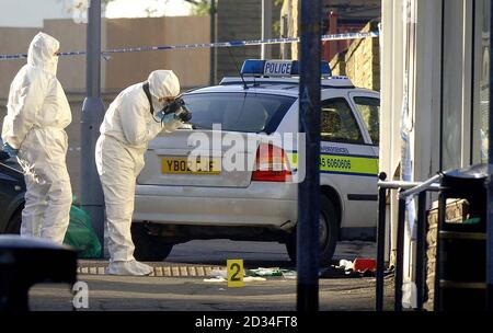 Re-transmitted to add caption information. Forensic teams examine the police patrol car used by officer Sharon Beshenivsky, 38, at the scene of her murder in Bradford, Saturday November 19, 2005. Pc Beshenivsky, who had three children and two step-children, was gunned down on her youngest daughter's fourth birthday as she arrived at the raid in a travel agent's shop on Friday 18th November. See PA story POLICE Officer. PRESS ASSOCIATION Photo. Photo credit should read: John Giles/PA Stock Photo