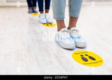 People Standing In Queue, Social Distancing Signs On Floor Indoors Stock Photo
