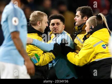 A pitch invader is escorted off the pitch during the Premier League match at the Etihad Stadium, Manchester. Stock Photo