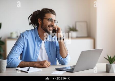 Young Indian Male Entrepreneur Talking On Mobile Phone At Office Stock Photo