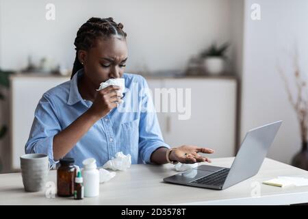 Sick Black Female Office Worker Taking Antivirus Pills On Workplace Stock Photo