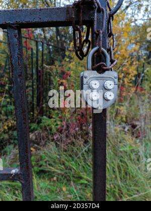 Old mechanical combination lock hanging rust fence gate door. Stock Photo