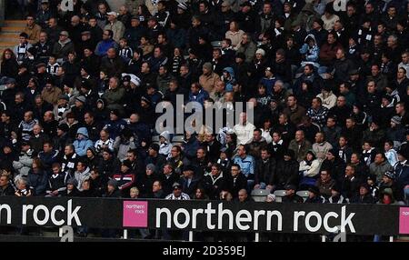 Newcastle supporters sit behind advertising boards for troubled Bank Northern Rock during the Barclays Premier League match at St James Park, Newcastle. Stock Photo