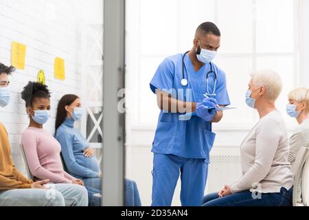 Doctor Taking Notes Talking With Senior Patient Lady In Hospital Stock Photo