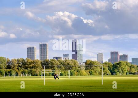 UK, London, Hackney. Footballers training on Hackney Marshes playing fields, with the skyscrapers of Stratford behind
