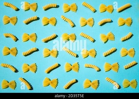 Uncooked curly pasta pattern on blue background. Traditional dry raw macaroni pattern. Nobody Stock Photo