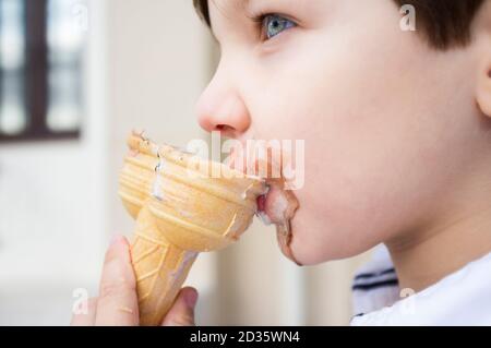 5 years old little licking twin cone ice cream. Selective focus Stock Photo