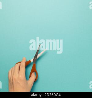 Scissors with hand on blue background. top view, copy space Stock Photo