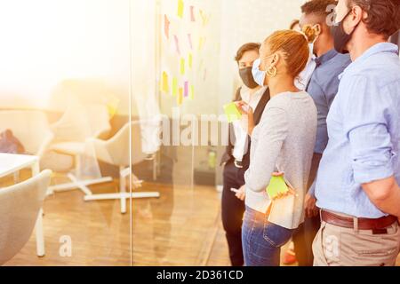 Start-up business team during coronavirus pandemic in the office with face mask because of Covid-19 Stock Photo
