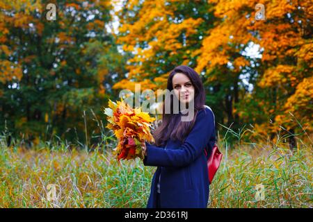 Happy woman making a wreath from maple leaves in autumn park. Fall concept Stock Photo