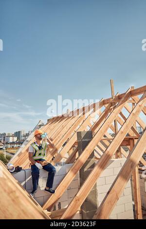 Hard-working man drinking water on a building rooftop Stock Photo