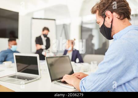 Business man with everyday mask doing online research on the laptop computer Stock Photo
