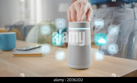 Man Turns On Smart Speaker with Active Artificial Intelligence Assistant with Futuristic Screenless Interface with Different Icons and Symbols. Stock Photo