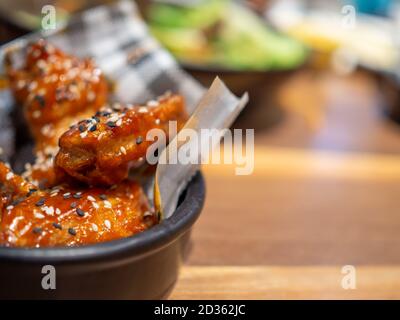 Korean BBQ chicken on a black plate placed on a wooden table and with a blurred background. Stock Photo