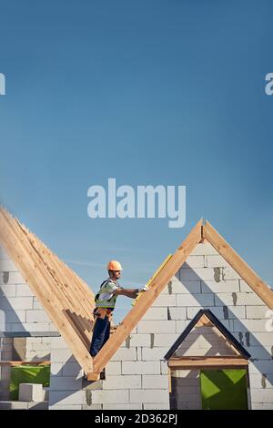 Experienced builder working on rooftop with a spirit level Stock Photo