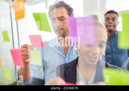 Start-up team analyzing ideas on slips of paper in a brainstorming workshop Stock Photo