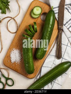 Long smooth cucumbers whole and cut into rings on a wooden Board  Stock Photo