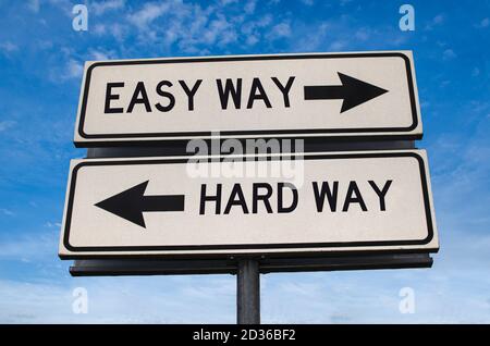 Easy way versus hard way road sign. White two street signs with arrow on metal pole with word. Directional road. Crossroads Road Sign, Two Arrow. Blue Stock Photo