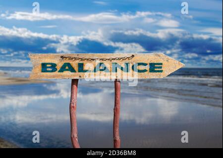 Balance wooden arrow road sign against beautiful marine landscape. Baltic sea during sunny day with beautiful clouds with gulls in the waves in Jurmal Stock Photo