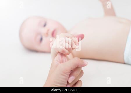 Cute baby girl holding mothers finger