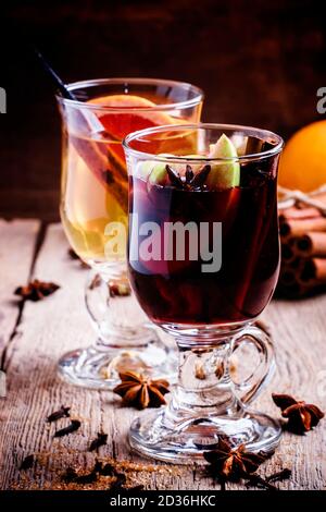 Hot mulled wine with white and red dry wine, spices and fruits, old wooden background, selective focus Stock Photo