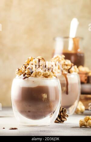 Cold chocolate dessert with whipped cream, popcorn and caramel topping in glasses on beige background, place for text Stock Photo