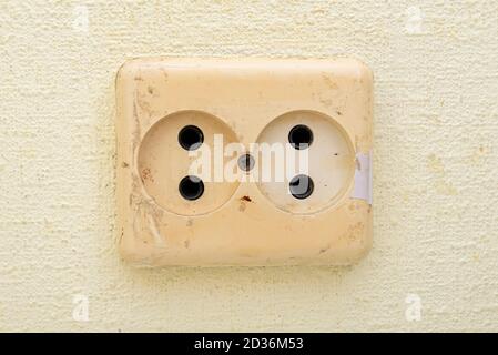 Dirty used electric power socket on old wall, room, interior Stock Photo