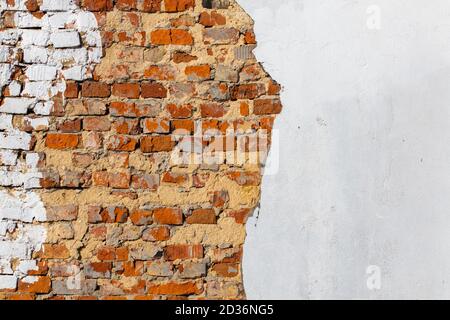 old bad brick wall with leftovers of white peeled thick plaster Stock Photo