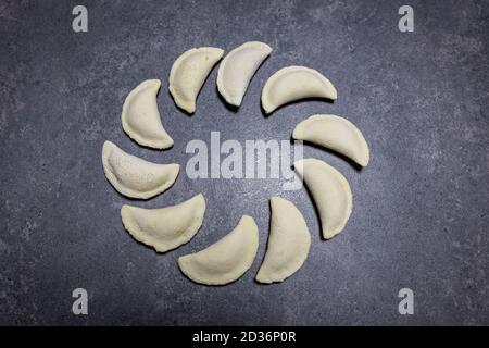 Polish gluten-free dumplings (Pierogi), polish national dish made of dough and savoury or sweet filling. Several frozen dumplings lying on a table. Stock Photo