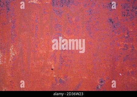 Background of rusty iron wall with cracked red paint. Stock Photo