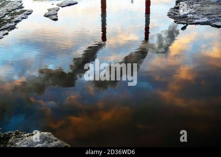 Reflection in puddle of three smoked industry chimneys. Air pollution concept Stock Photo