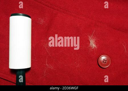 Lint remover roller on red clothes and cat hair, top view Stock Photo