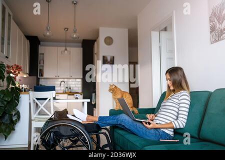 Disabled young woman using laptop while sitting on sofa at home Stock Photo