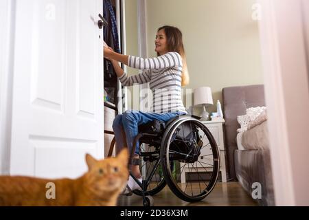 Woman in wheelchair sorts through her wardrobe Stock Photo