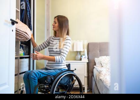 Woman in wheelchair sorts through her wardrobe Stock Photo