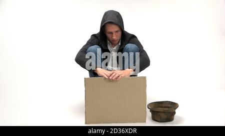 Sad young man sits with blank cardboard sign. Stock Photo