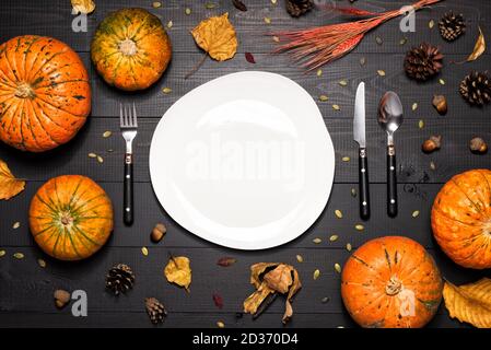 Autumn table setting with empty white plate and pumpkins. Stock Photo