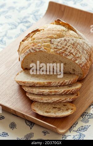 Loaf of sliced sourdough bread on cutting board. Stock Photo
