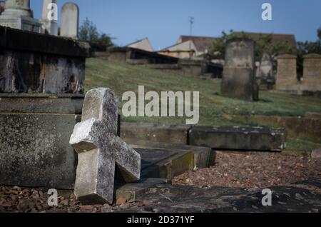 A broken cross on the graveyard floor Stock Photo