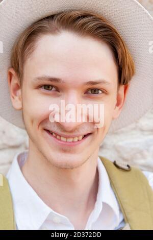 Young caucasian man wearing a white hat smiles at the camera. Close-up Stock Photo