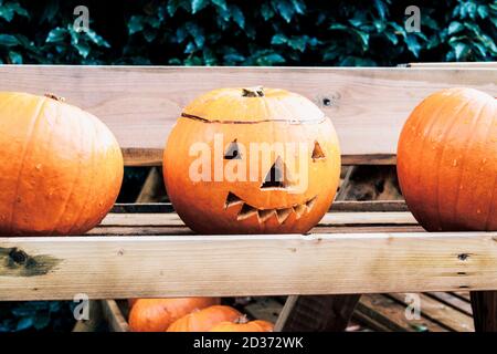 Three pumpkins on a wooden rack, the centre one have a Halloween face carved into it Stock Photo