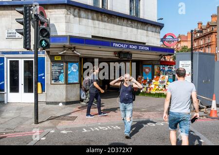 Pedestrians crossing the road outside Finchley Road Underground Station on an unusually warm late September afternoon, London, UK Stock Photo