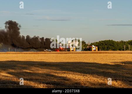Smoke rising from a combine harvester with a fire engine in attendance, Ardleigh, Essex, UK. Stock Photo